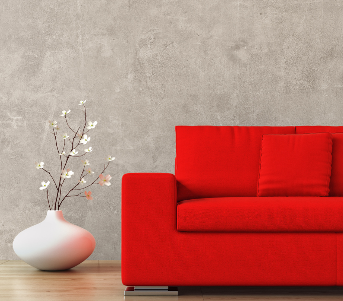 Sofá vermelho com padrão quadriculado ao lado de vaso branco com galhos secos em fundo cinza com padrões.